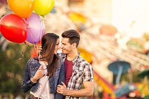 Romantic couple in the amusement park holding balloons.