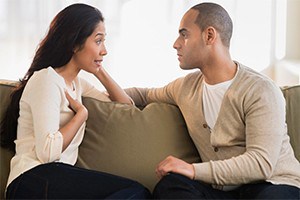 Couple sitting on couch having a serious talk.